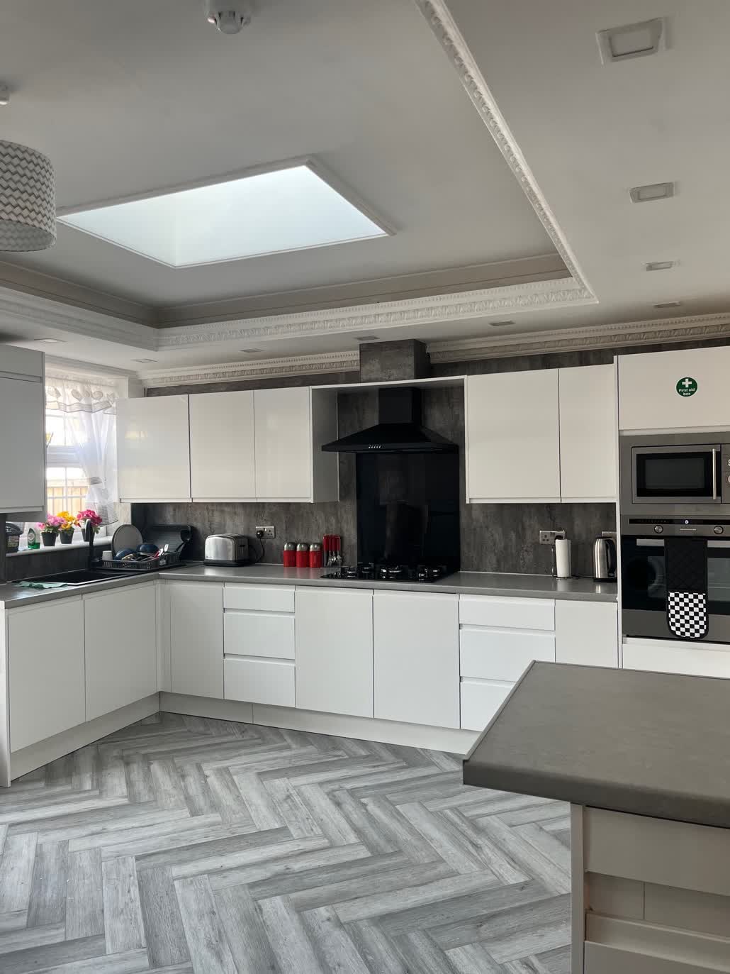 Bright modern kitchen with white units and herringbone flooring